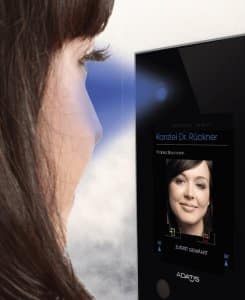 A photo of a woman standing in front of an Adatis facial recognition panel as it scans her face.