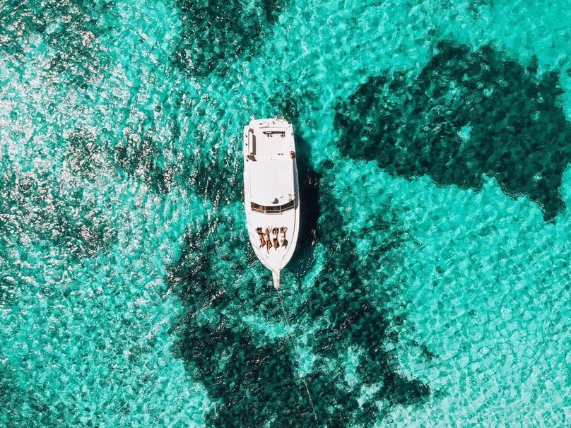 A photo birds eye view of of a luxury yacht anchored in crystal clear waters.
