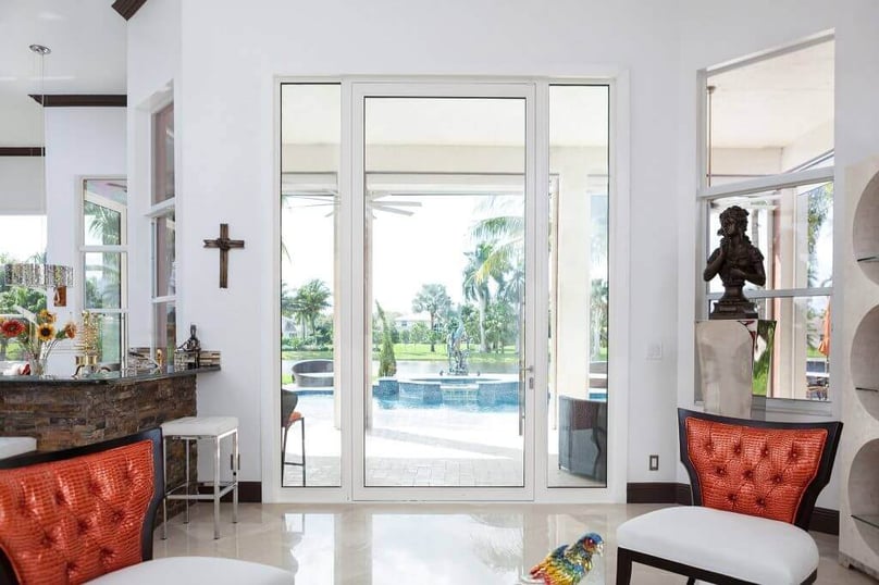 A photo of a bright, elegant dining room that opens up to a patio through a large glass door.