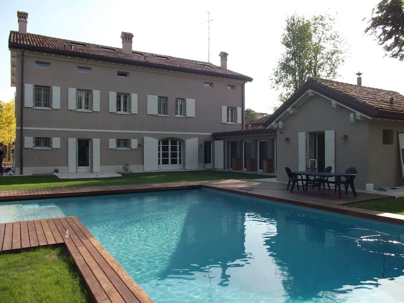 A photo of a pristine pool in the backyard of a luxury home featuring security doors and windows.