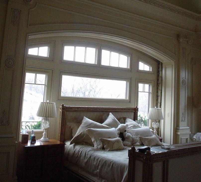 A photo of a bed surrounded by security windows in the master bedroom of a luxury home.
