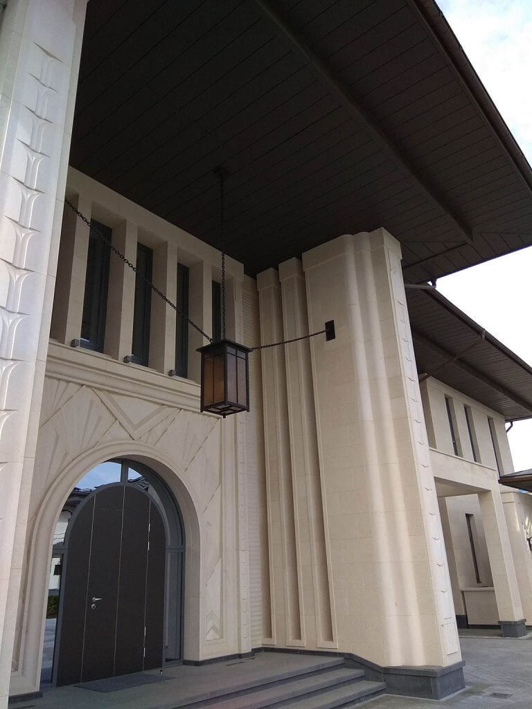 A photo of the grand entrance of a very large luxury home, complete with an arched front door and a chandelier. 