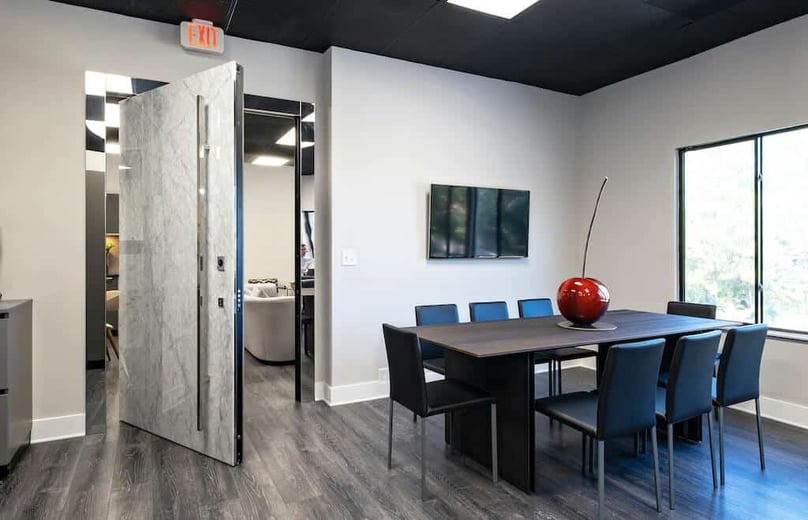 A photo of the interior side of a pivot door covered in marble in an upscale office.