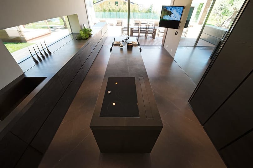 A photo of a kitchen in a luxury home overlooking a patio and a pool.