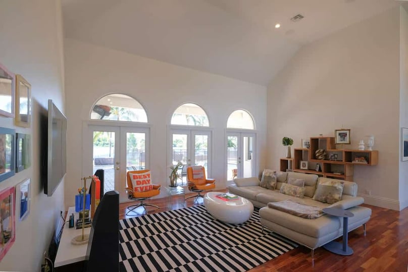  A photo of a brightly lit living room in a luxury home featuring large security windows and glass doors.