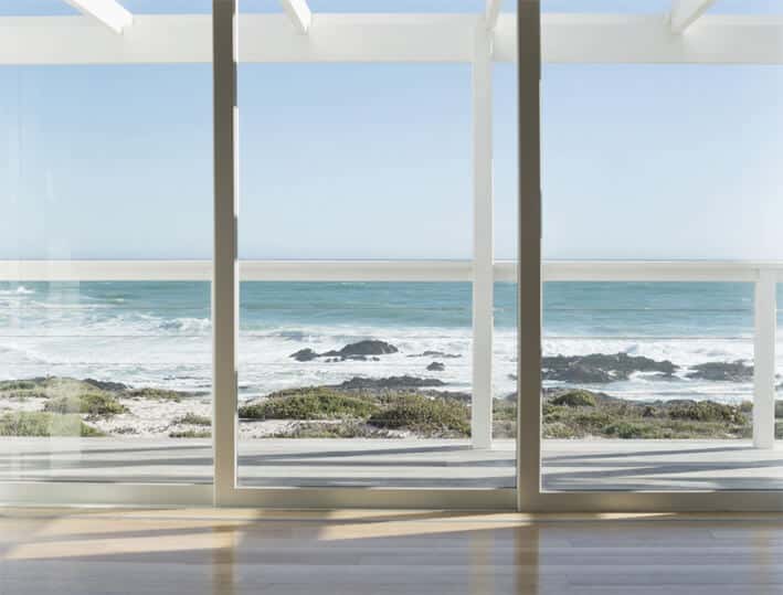 A photo of a sliding glass door made from security glass overlooking an ocean view.