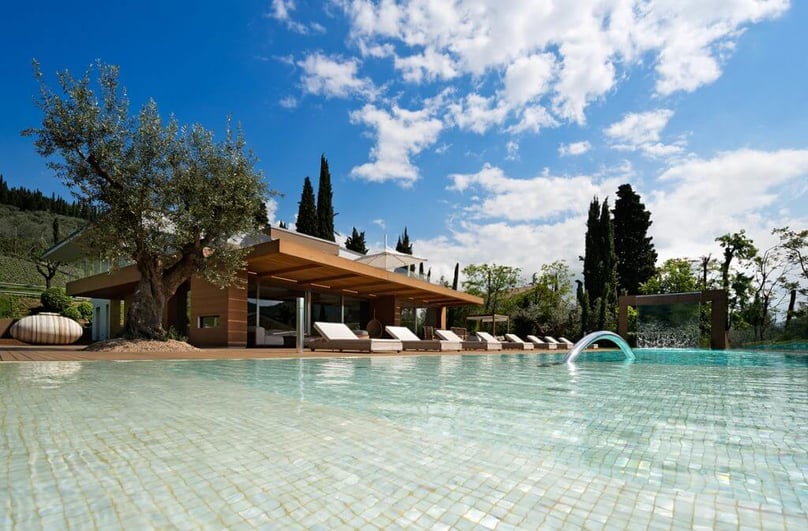  A photo of a luxury home with a large pool and multiple lounge chairs awaiting party guests.