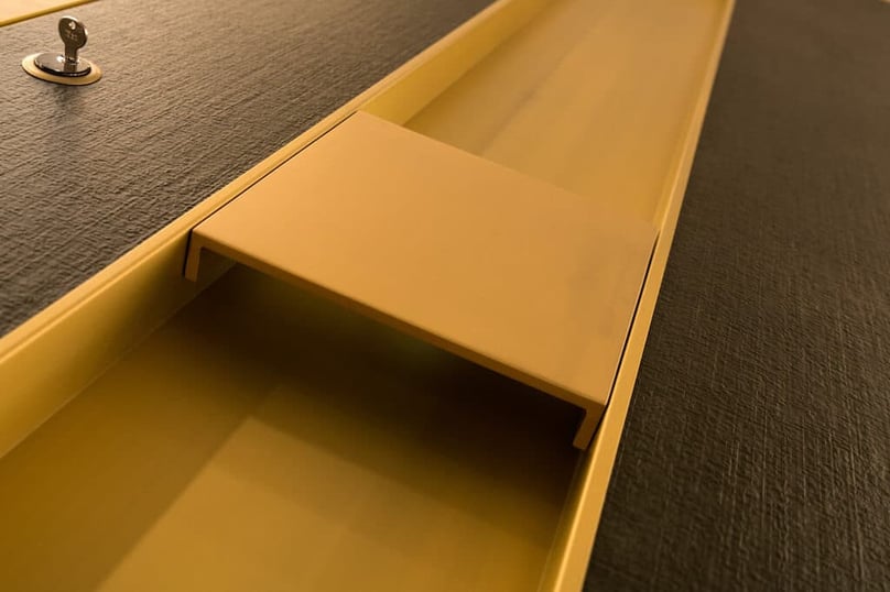  A close-up photo of a gold-finished luxury door handle in a recess of a custom security door.