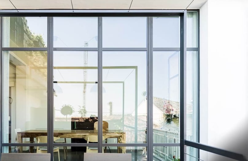 A photo of a wall of windows dividing a modern living space and an outdoor patio.